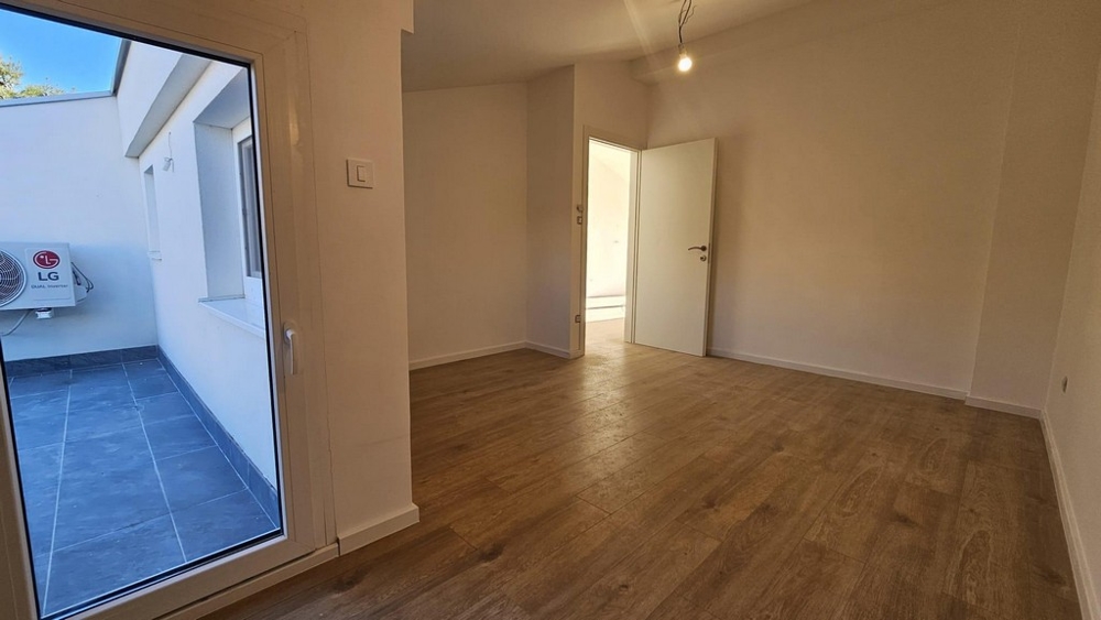 Napfényes teraszra vezető, világos szoba fapadlóval és fehér falakkal Crikvenicán eladó lakásban