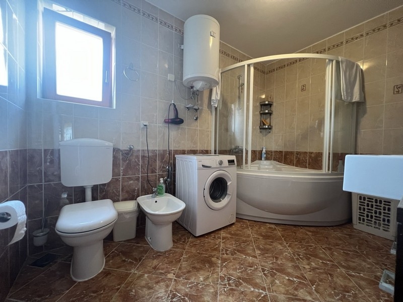 Nagy fürdőszoba zuhanyzóval és mosógéppel.