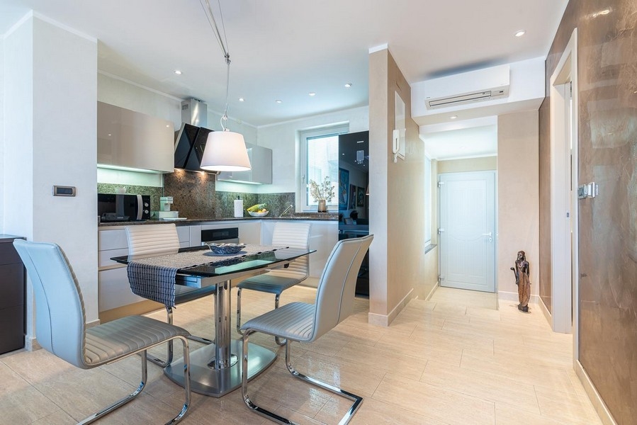 Modern étkező üvegasztallal, kilátással a modern konyhára és a légkondicionált bejáratra.