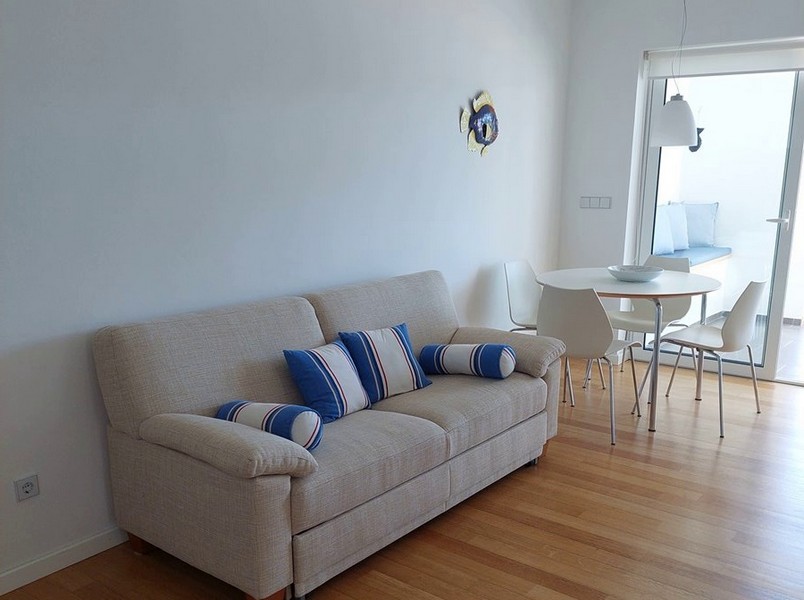 Világos krémszínű kanapé és étkező, kilátással a teraszra.