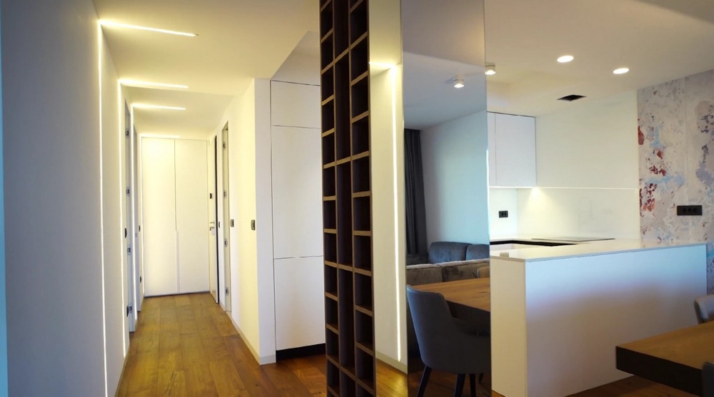 Hosszú előszoba egy modern lakásban a horvát tengerparton, beépített szekrényekkel és fapadlóval.
