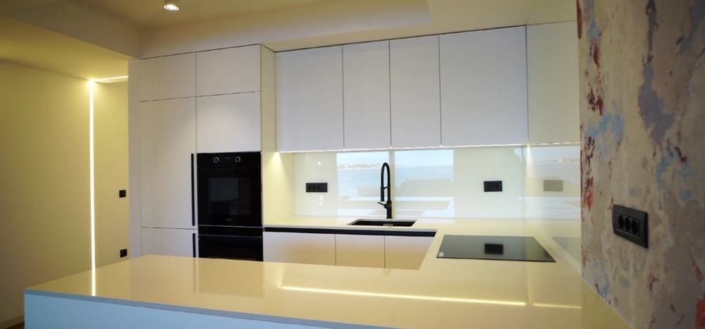 Ultramodern konyha egy tengerparti ingatlanban Horvátországban fehér szekrényekkel és központi konyhablokkokkal