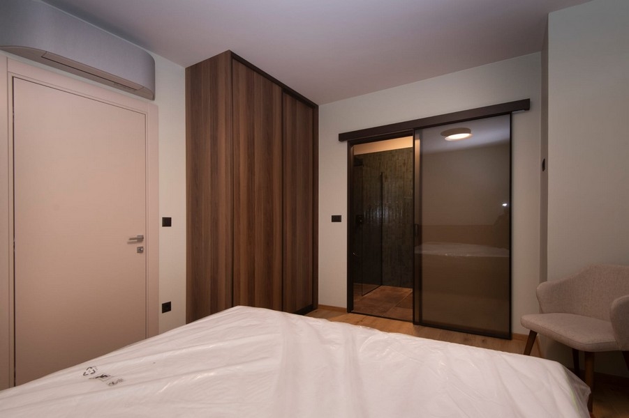 A horvátországi Splitben eladó hálószoba közvetlen fürdőszobával egy modern lakásban, nagy ággyal és elegáns bútorokkal.