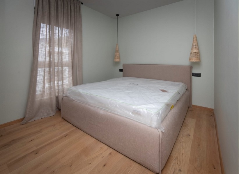 Egyszerű, remekmű hálószoba egy modern apartmanban Splitben, Horvátországban, minimalista dizájnnal és semleges tónusokkal.