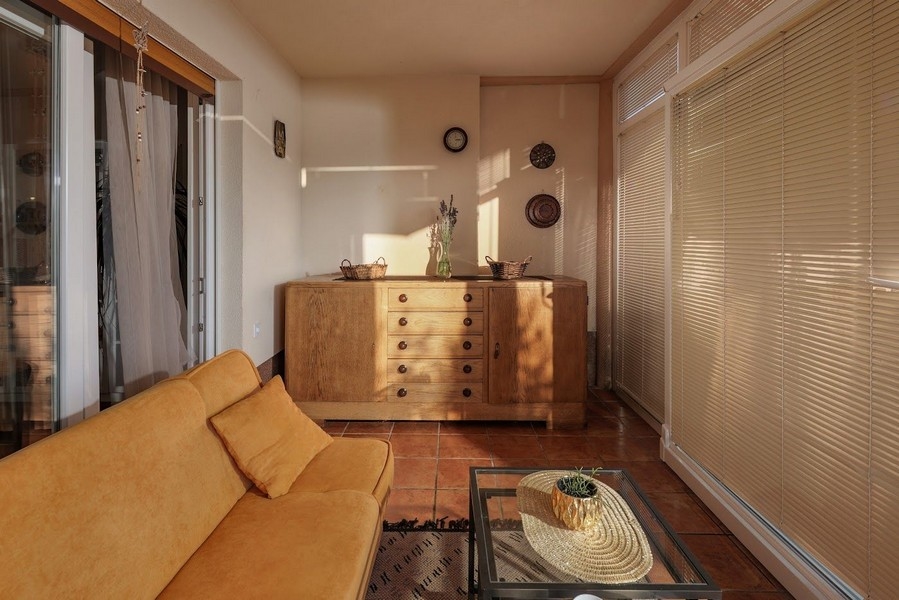 Egy horvát lakás napfényes télikertje sárga kanapéval.