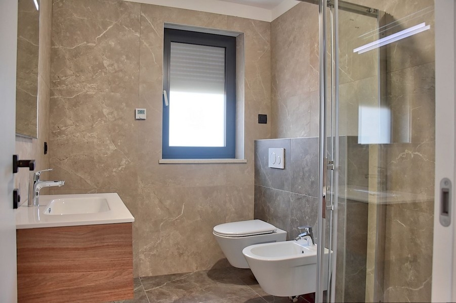 Elegáns tetőtéri fürdőszoba eladó Isztrián, modern szerelvényekkel és márvány csempével.