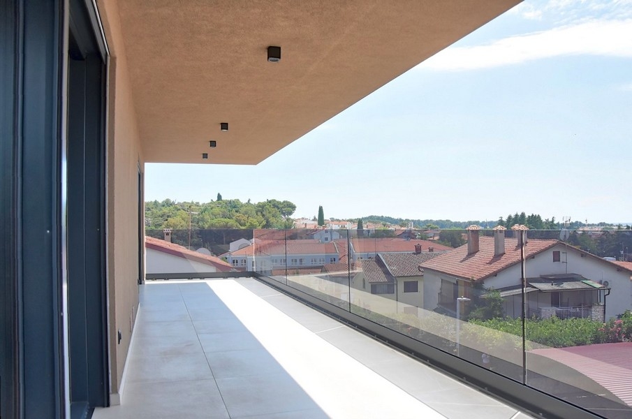 Egy isztriai penthouse fedett erkélye, kilátással a helyi építészetre és a tengerre.