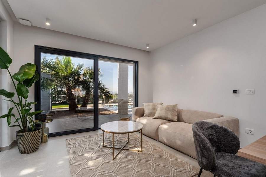 Világos nappali egy isztriai luxuslakásban, nagy ablakkal a kertre és stílusos bútorokkal