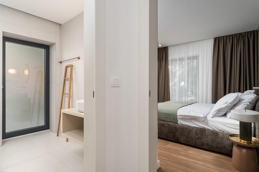 Hangulatos hálószoba egy isztriai luxuslakásban, közvetlen hozzáféréssel a fürdőszobához és modern belső terekkel