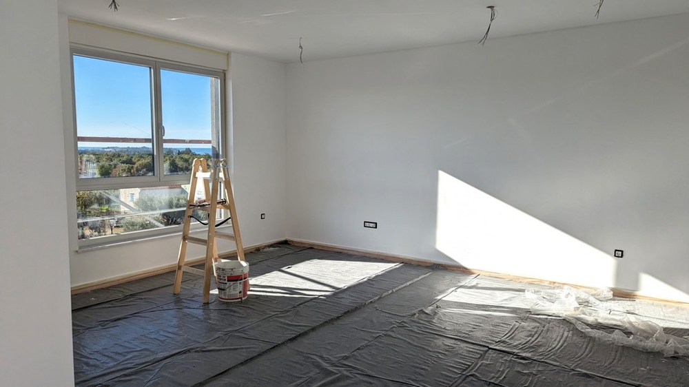 Világos, felújítás alatt álló szoba létrával és festési kellékekkel, egy isztriai luxusingatlan része.