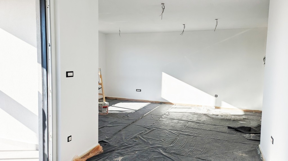 Tágas, napsütötte szoba védőfóliával a padlón, Isztria első osztályú lakásának építése során