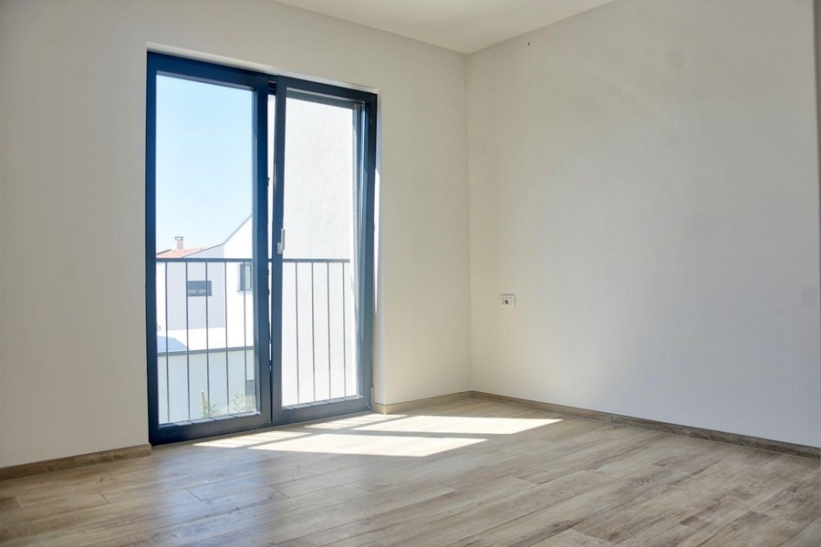 Erkélyajtós, laminált padlós világos hálószoba, mely része az ingatlanajánlatnak Porecen