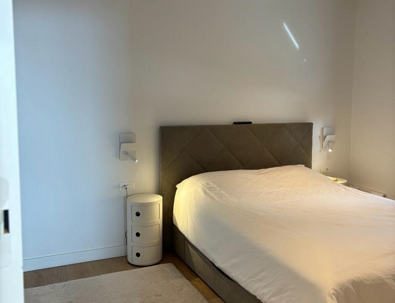 Minimalista hálószoba nagy ággyal és éjjeliszekrénnyel, ingatlan része Rijekában, Horvátországban.