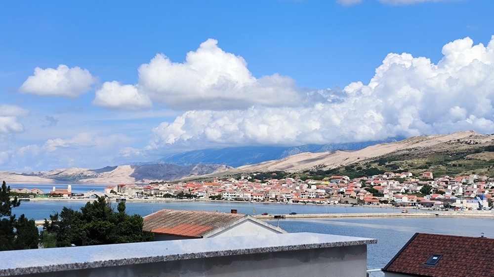 A horvátországi Pagban eladó lakás parkolójának külső nézete, murvás ösvényen