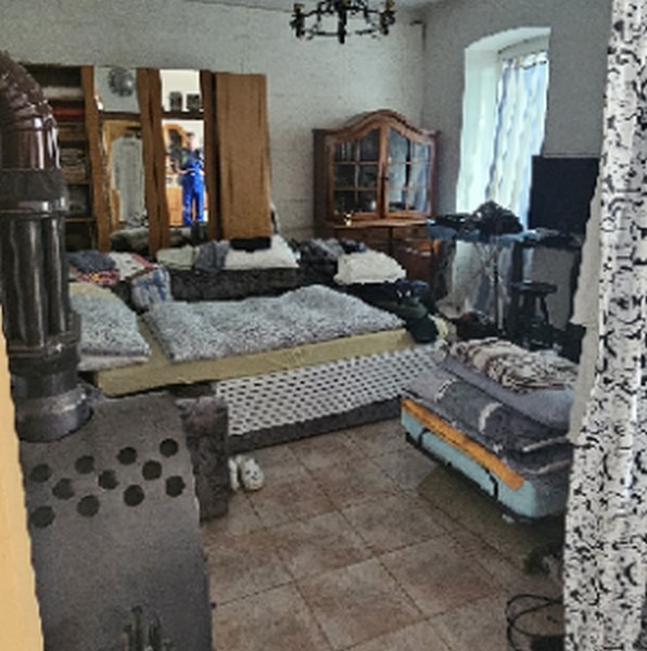 Nappali több kanapéval és fatüzelésű kályhával, tükörrel és televízióval