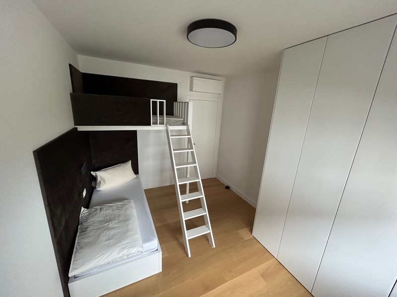 Minimalista hálószoba tetőtéri ággyal és létrával egy modern apartmanban Rijekában.