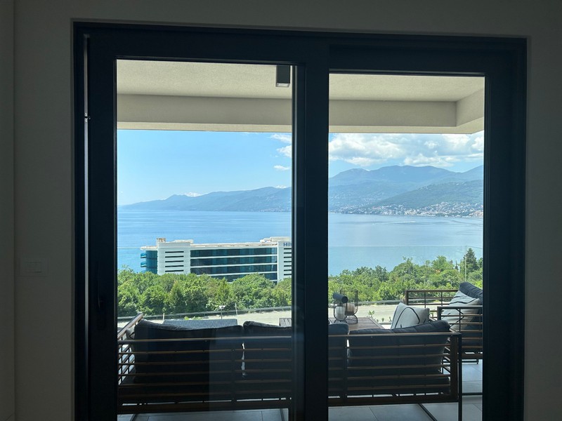 Kilátás egy modern apartman nyitott teraszajtaján, kilátással a Kvarner-öbölre.