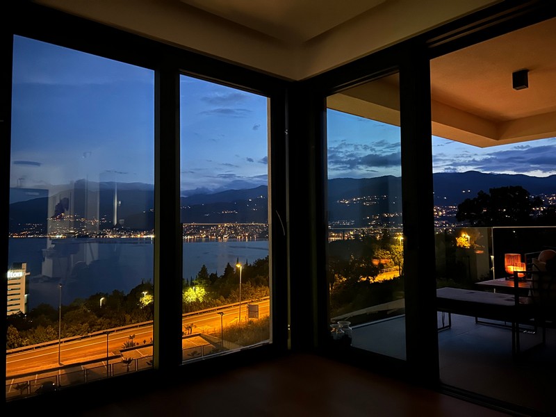 Éjszakai kilátás egy rijekai apartman erkélyéről, kilátással a megvilágított tengerpartra.