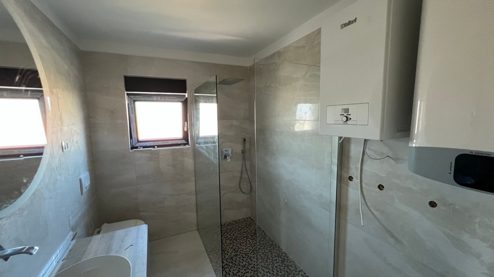 Elegáns fürdőszoba modern zuhanyzóval, amely a kiváló minőségű horvátországi ingatlanokra jellemző.