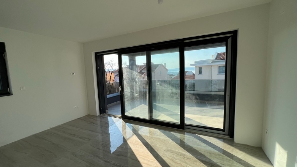 A Krk-szigeten található ingatlan modern koncepciójába illeszkedik a világos nappali padlótól a mennyezetig érő ablakokkal.