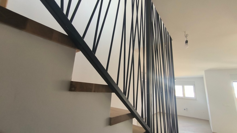 Belső lépcsőház modern korláttal a penthouse-ban, horvátországi ingatlan Simuniban, mely ötvözi az eleganciát és a dizájnt.