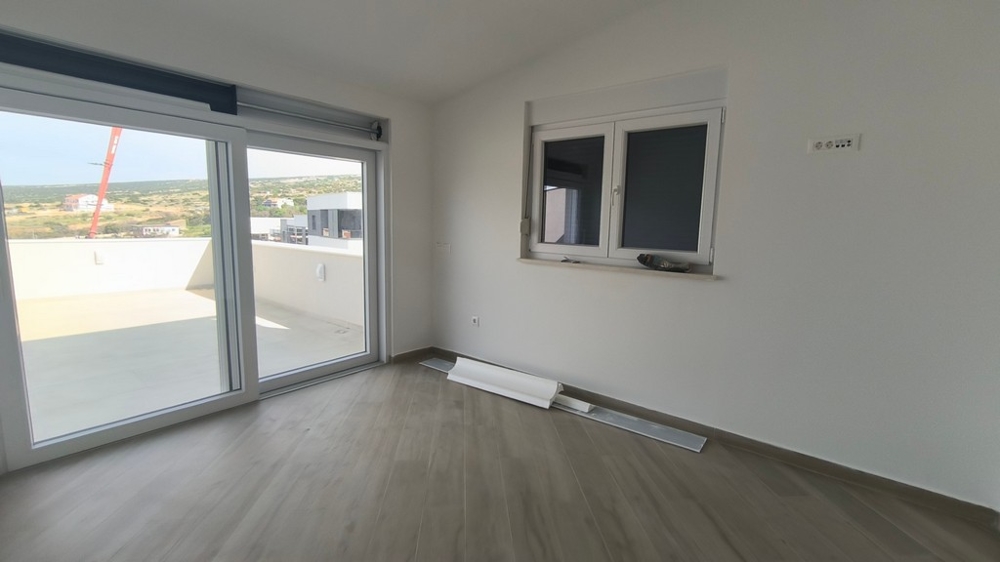 Világos, modern nappali egy penthouse, horvátországi ingatlan Simuniban, terasszal és tengerre néző kilátással.