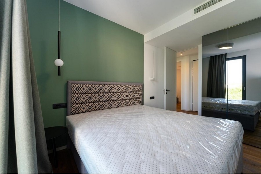 A hálószoba zöldre festett falakkal és tükrös gardróbbal