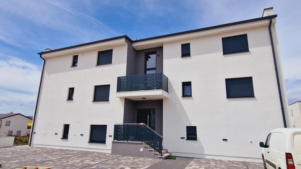 Egy modern épület elölnézete fehér falakkal és fémkorlátokkal ellátott erkélyekkel