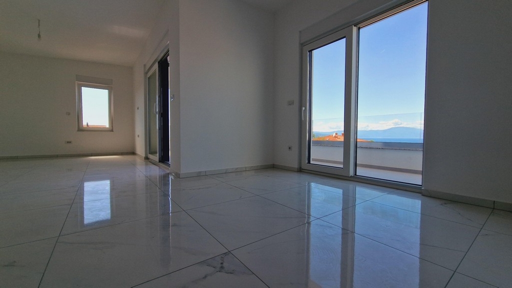 Egy apartman belseje nagy ablakokkal és tengerre néző kilátással