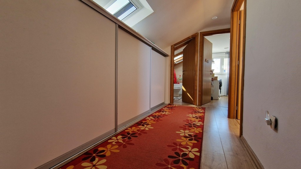 Folyosó vörös szőnyeggel és szekrényekkel a tető alatt