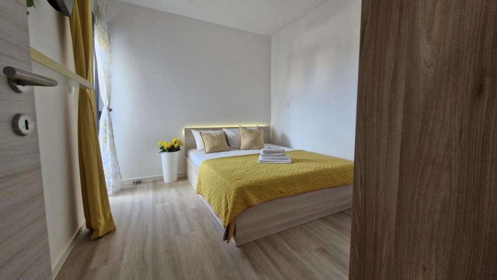 Hálószoba franciaággyal, sárga paplannal és dekorációval