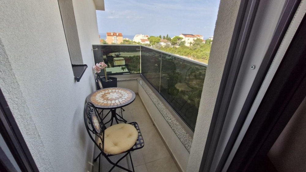 Erkély kis asztallal és két székkel, kilátással a szomszédos épületekre