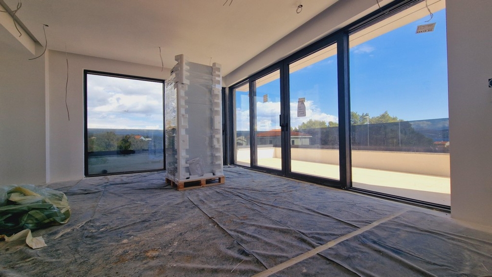 A modern, új lakás belső nézete nagy ablakokkal, kilátással a teraszra és a tengerre.