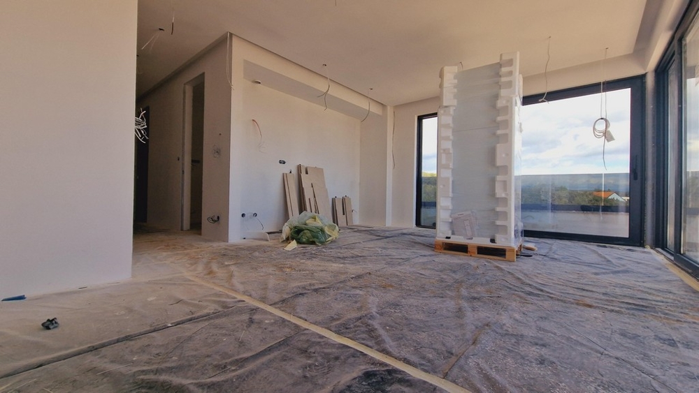 Az elkészült új épület lakóterülete, kilátással a nagy üvegablakra és a környező természetre.