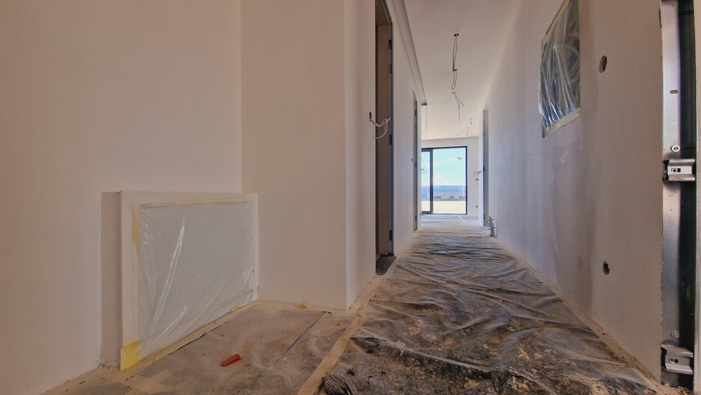 Az építési fázisban lévő új épület folyosója, kilátással a folyosó végén lévő teraszra.