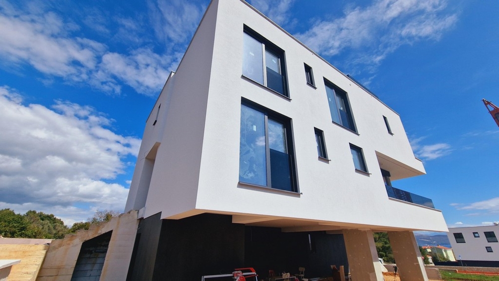 A modern új épület külső képe tiszta, fehér homlokzattal és több nagy ablakkal.