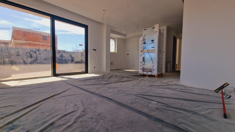 Az új lakás belső nézete nagy ablakokkal és tiszta kilátással a teraszra és a környező területre.