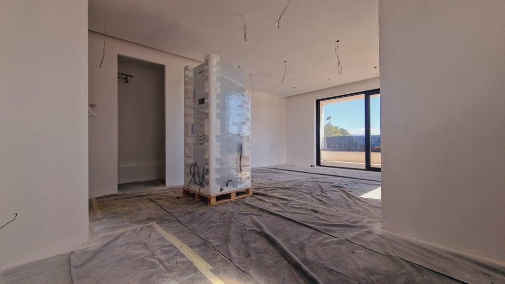 Nagy nappali egy modern, új épületben, még építés alatt, ablakos előlappal és kijárattal a teraszra.