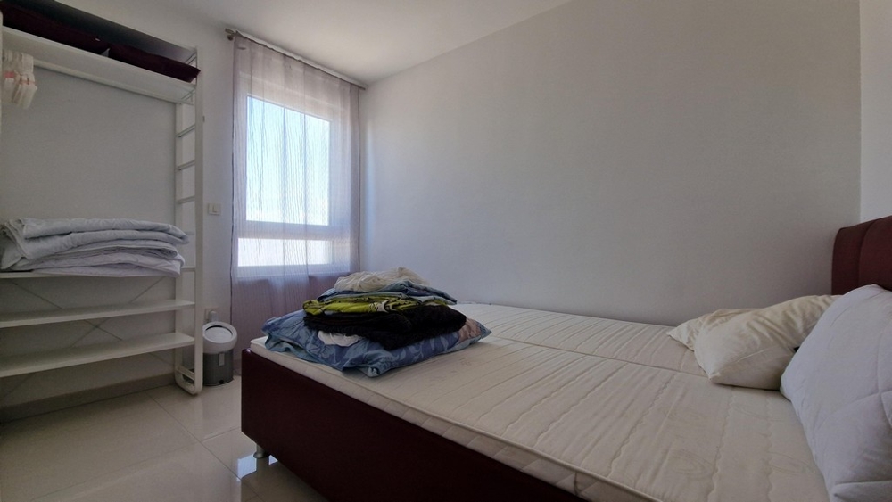 Hálószoba minimalista bútorokkal, ablakkal és nyitott ruhatárolóval.