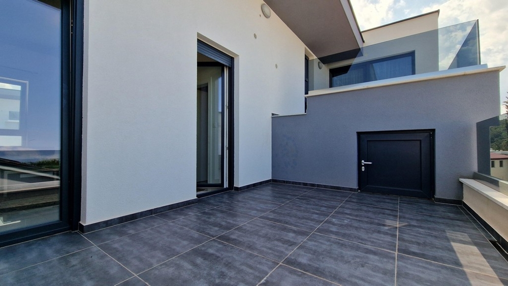 Modern terasz szürke csempével, üveg korlátokkal és bejárattal a lakásba.