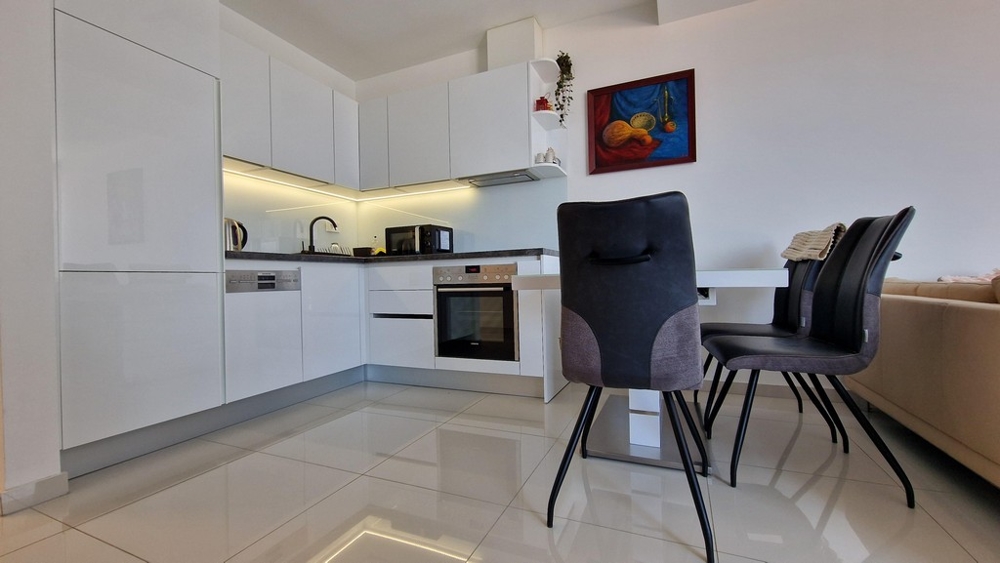 Tágas, nyitott konyha étkezővel, modern berendezéssel, beépített gépekkel.