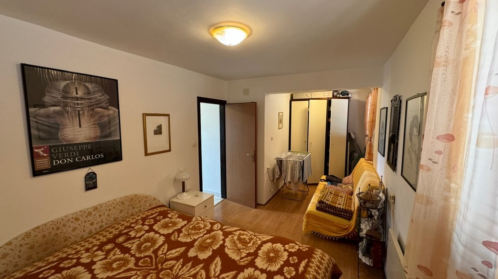 Tágas hálószoba további ülőhellyel, képekkel díszítve.