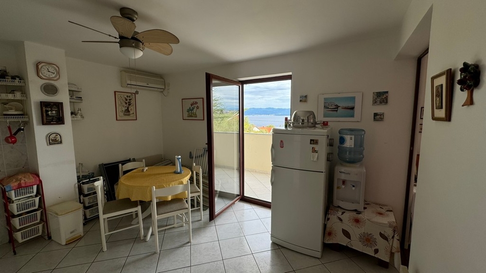 Világos nappali étkezőasztallal, légkondicionálóval és hozzáféréssel a tengerre néző teraszhoz.