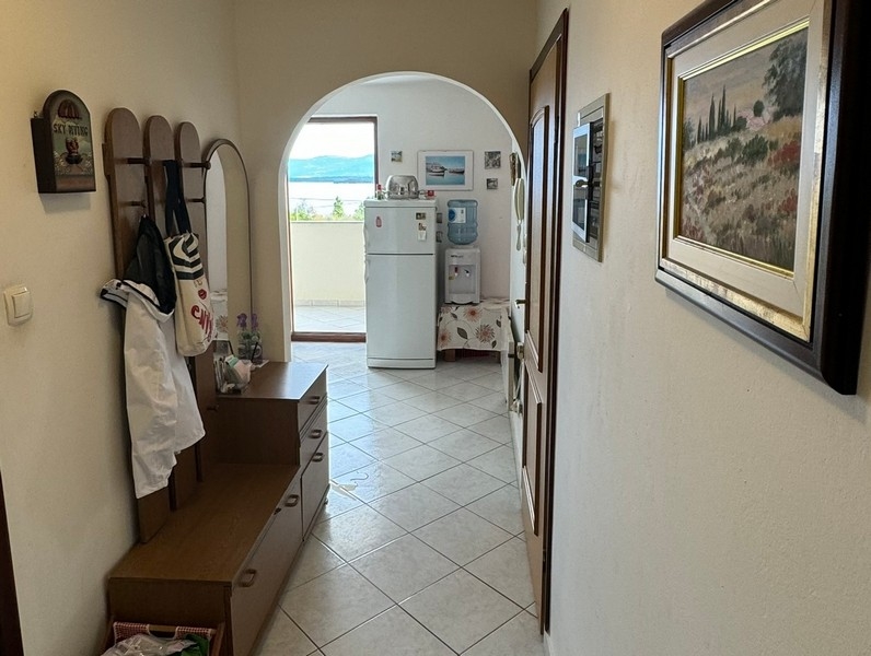 Előszoba gardróbbal, kilátással az étkezőre, nagy boltívvel és csempézett padlóval.