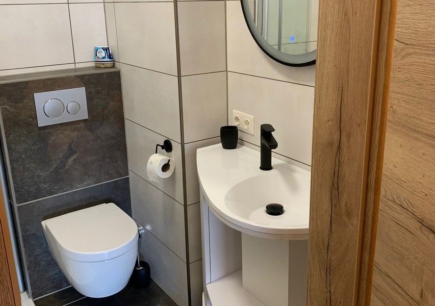 Modern fürdőszoba WC-vel, mosdóval és stílusos csempével.