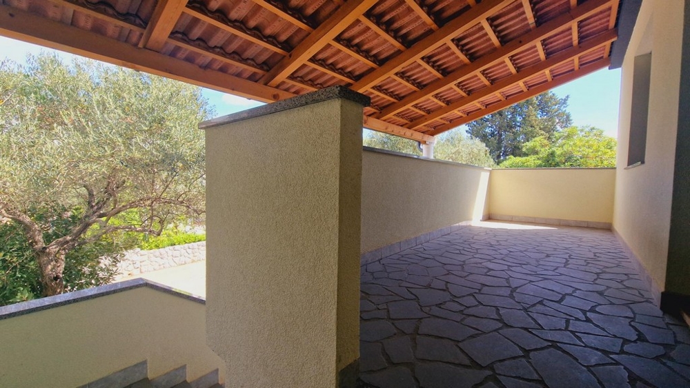 Fedett szabadtéri terület kőpadlóval, kilátással a fákra és a természetre.