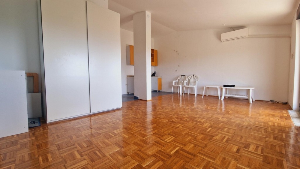 Tágas nappali parkettával, légkondicionálóval és minimalista bútorokkal.