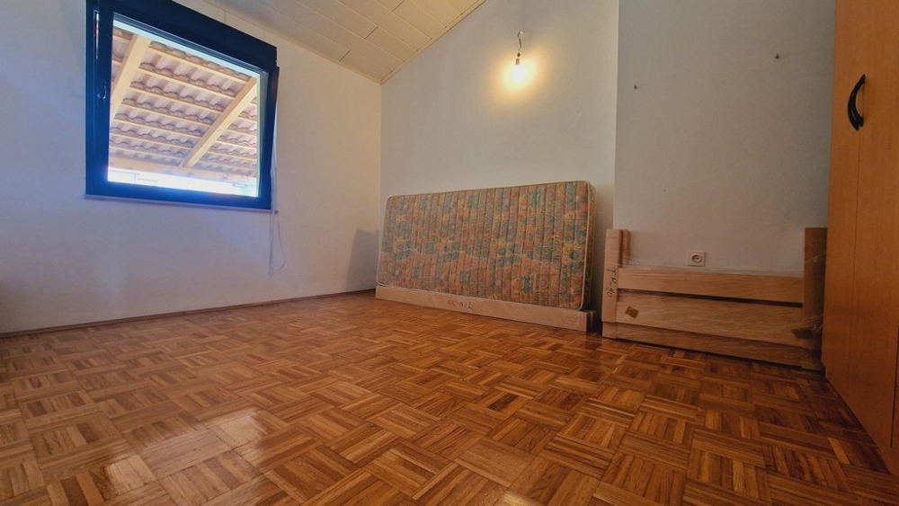 Fapadlós hálószoba ablakos, részben bútorozott szoba.