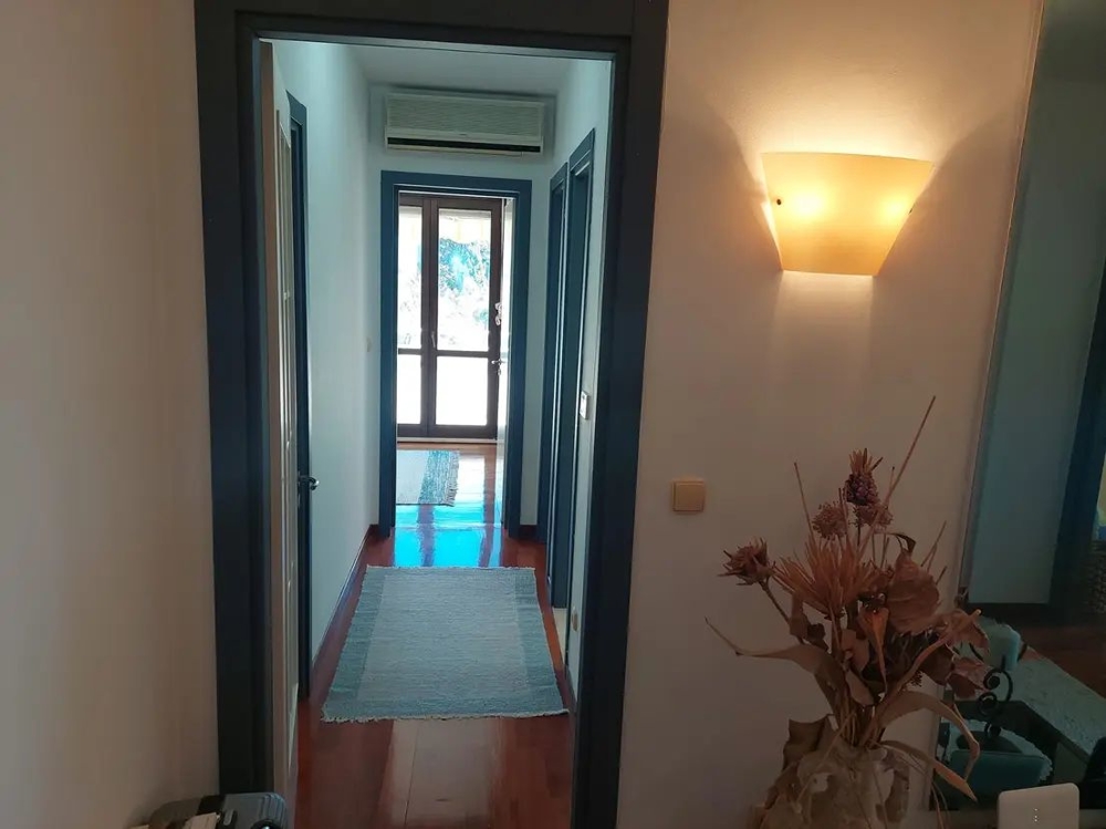 Világos falakkal és fapadlóval ellátott folyosó, modern berendezésű bejárat