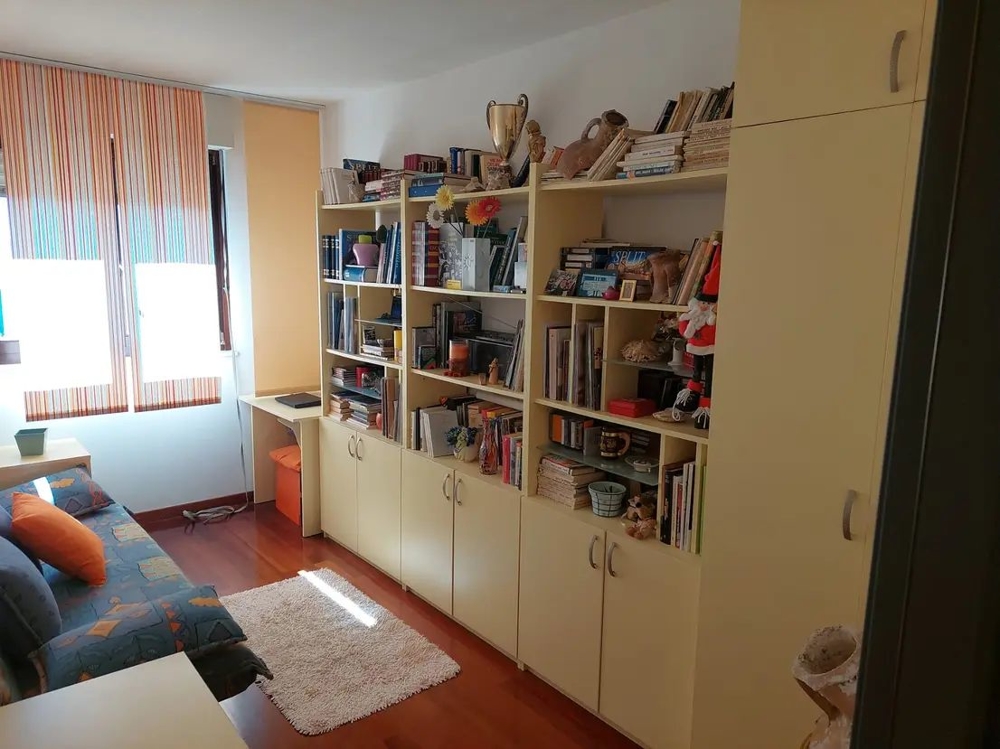 Szoba könyvespolcokkal, íróasztallal és kanapéval, világos ablakokkal